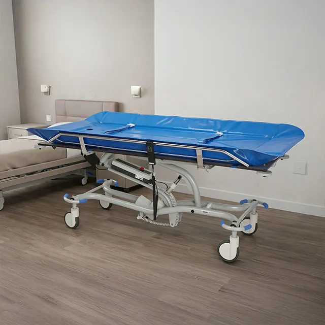 Brancard d'hôpital réglable sur roulettes avec matelas bleu imperméable installé dans une chambre au sol en bois.