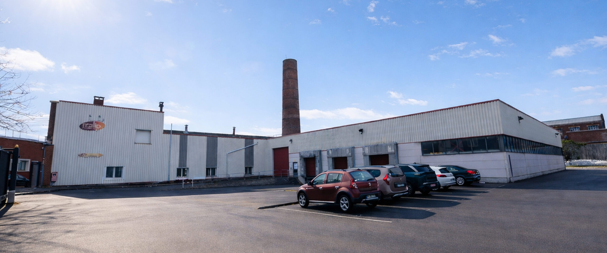 Vue extérieure du site de production MALIP avec bâtiment et stationnement